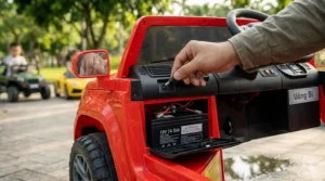 A photorealistic 4K close-up illustration showing an adult's hand connecting a specialized power adapter to a concealed charging port to recharge the internal 12V battery inside a red electric ride-on toy.