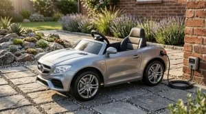 A detailed silver electric ride-on toy car with complex alloy wheels, parked on a textured stone paver patio.