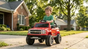 A 3-year-old boy driving a red battery-powered toy truck on a sidewalk, perfect for outdoor ride-on toy play.