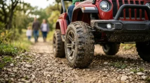 Large EVA rubber tires of a 24V ride-on toy navigating gravel and dirt paths easily.