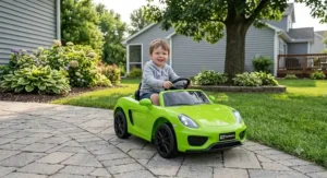 Smiling little boy sitting in a lime green ride on supercar on a backyard path.