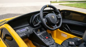 Interior view of the steering wheel, dashboard buttons, and media player on a licensed Lamborghini Aventador ride on car.