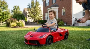A young child smiling while driving a red LaFerrari ride on car with remote control in a backyard.