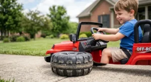 Child turning the steering wheel of a 12 volt ride on truck with all terrain rubber tires.