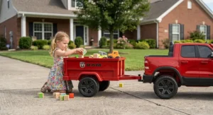 A little girl loading toy blocks into the detachable trailer of a Ram truck ride on toy.
