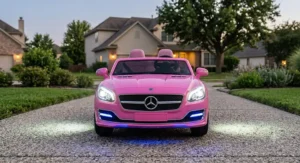 Front view illustration showing illuminated LED headlights on a pink 2 seater luxury ride on car for toddlers