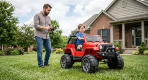 Parent using a wireless remote control while a child rides in a lifted ride on truck with rubber tires.