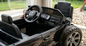 Detailed view of the dashboard and rugged wheels on a children's Ram truck ride-on toy with a trailer.