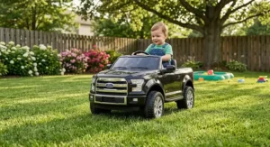 Toddler driving a black Ford F150 ride on truck on the backyard grass.