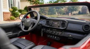 Interior view of a 2-seater Toyota Tacoma ride-on car showing dashboard controls, steering wheel, and sound system