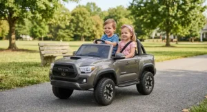 Two young siblings sitting together in a 2-seater Toyota Tacoma ride-on car during outdoor playtime