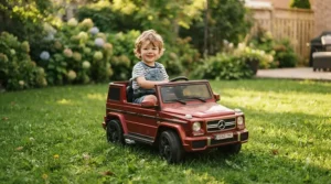 A happy young child steering a pink battery-powered toddler car across a green backyard lawn.