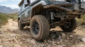 An off-road ride-on car for preteens tackling a rocky hillside with visible suspension movement.