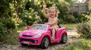 Little girl waving from inside a pastel pink convertible ride-on car for 3 year old