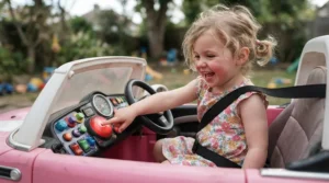 A preschooler using large adaptive switch controls on a ride-on car for preschooler with disability.