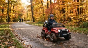 A rugged ride-on truck for 7 year old boy exploring a paved park path under autumn trees.