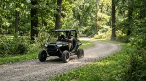 A premium adult ride-on car cruising along a paved path in a scenic city park