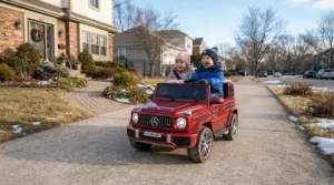 Two kids driving their two seater ride on car for Christmas gift down a suburban driveway